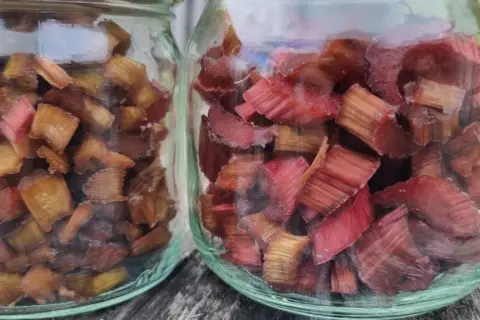 Två glasburkar fyllda med torkad rabarber, redo att användas i bakverk eller drycker.