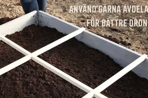 En pallkrage fylld med jord, redo för plantering. Avdelare i trä hjälper till att organisera och ger en bra uppfattning om hur mycket jord i en pallkrage som behövs.