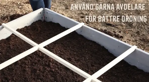 En pallkrage fylld med jord, redo för plantering. Avdelare i trä hjälper till att organisera och ger en bra uppfattning om hur mycket jord i en pallkrage som behövs.