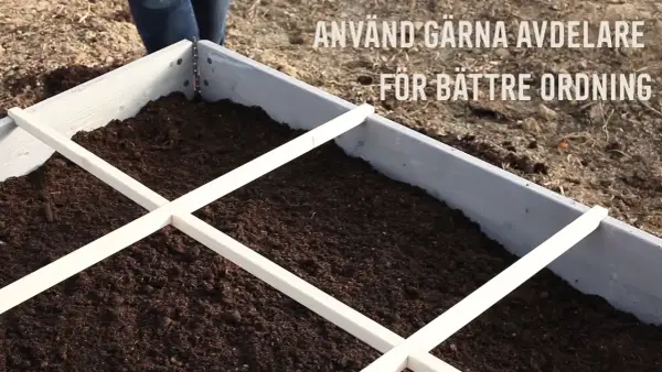 En pallkrage fylld med jord, redo för plantering. Avdelare i trä hjälper till att organisera och ger en bra uppfattning om hur mycket jord i en pallkrage som behövs.